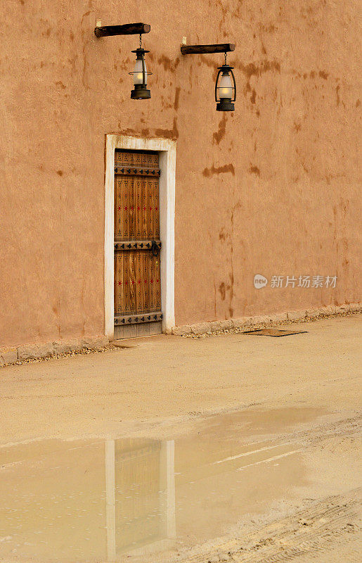 旧墙上的门，najdi装饰——雨天的水坑倒影——Ad Diriyah, At-Turaif区，联合国教科文组织世界遗产，利雅得，沙特阿拉伯